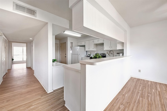 kitchen with visible vents, light wood-style flooring, freestanding refrigerator, and a sink