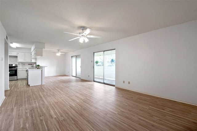 unfurnished living room featuring light wood finished floors, ceiling fan, and a sink