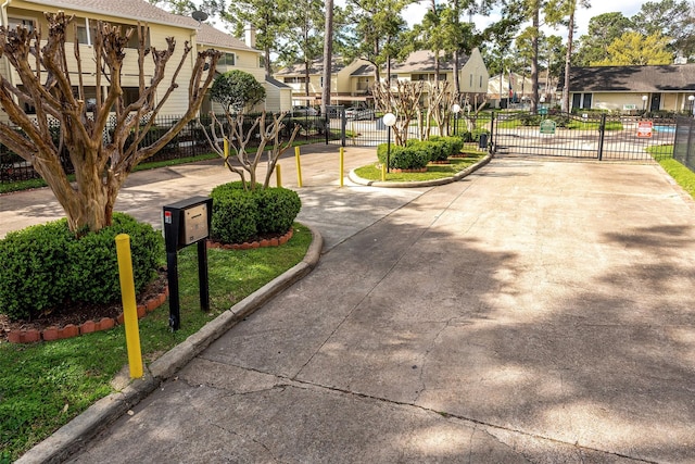 view of street featuring a gate, curbs, a residential view, and a gated entry