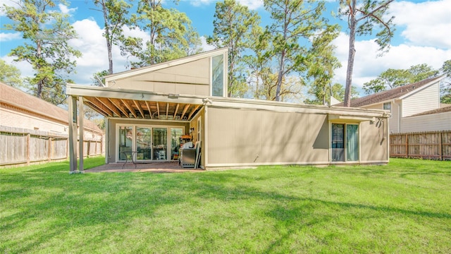 rear view of property featuring a fenced backyard, a patio, and a yard