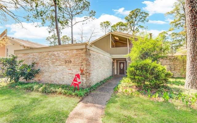 property entrance with a yard, fence, and brick siding