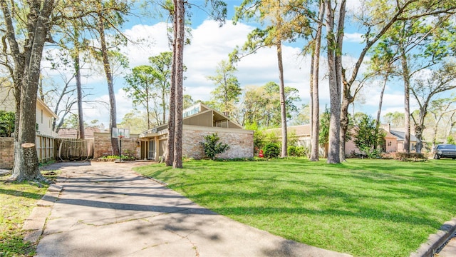 exterior space featuring concrete driveway, a yard, and brick siding