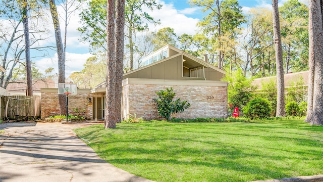 mid-century inspired home with brick siding and a front yard