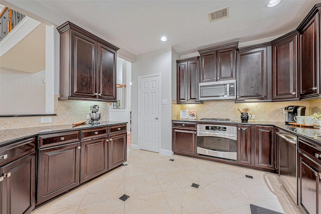 kitchen with backsplash, dark brown cabinets, visible vents, and appliances with stainless steel finishes