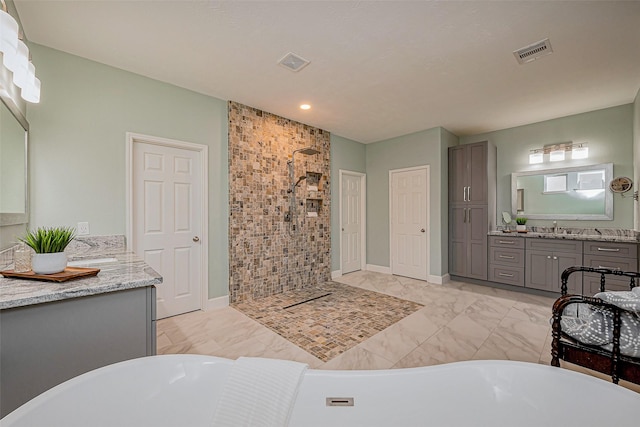 bathroom with visible vents, a freestanding bath, a tile shower, marble finish floor, and vanity