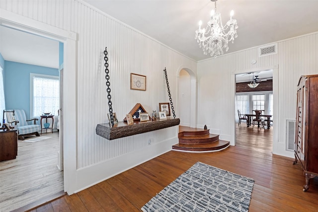 hall featuring an inviting chandelier, hardwood / wood-style flooring, plenty of natural light, and arched walkways