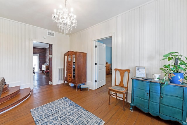 living area with a chandelier, visible vents, crown molding, and hardwood / wood-style floors