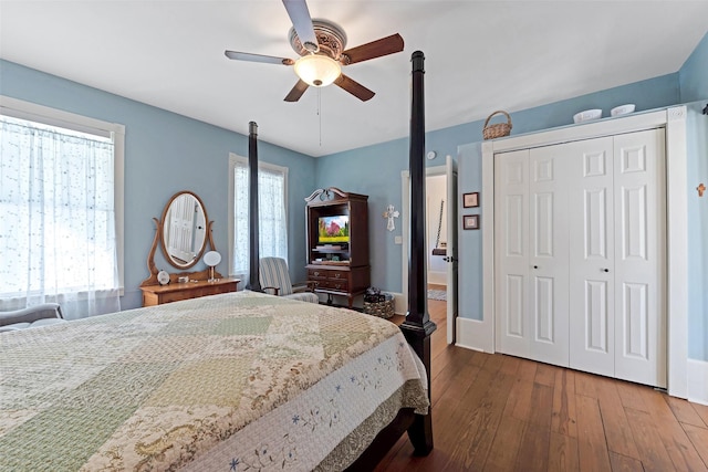 bedroom with dark wood finished floors, a ceiling fan, a closet, and baseboards