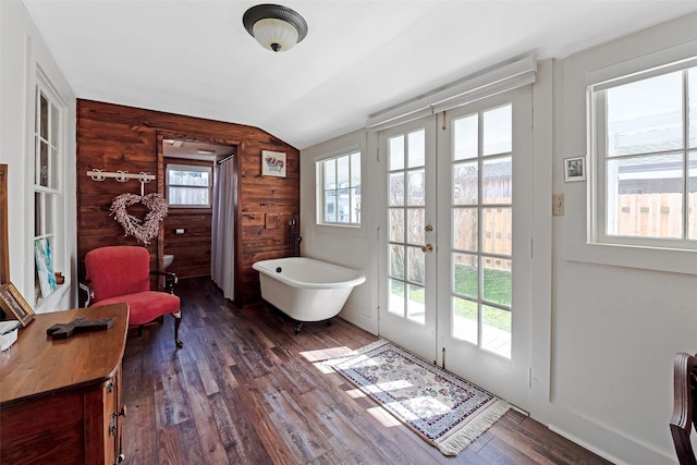 bathroom featuring wood walls, a freestanding bath, vaulted ceiling, french doors, and wood finished floors