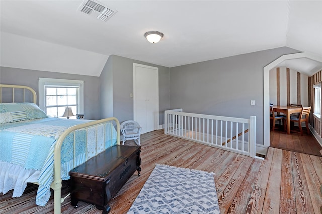 bedroom featuring visible vents, wood finished floors, and vaulted ceiling