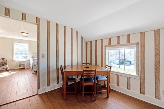 dining area with baseboards, hardwood / wood-style flooring, vaulted ceiling, and wallpapered walls