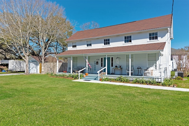 view of front of property featuring a front lawn, fence, a porch, cooling unit, and an outdoor structure