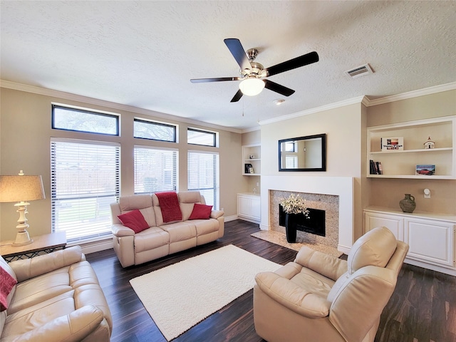 living room with dark wood-type flooring, built in shelves, a premium fireplace, and a textured ceiling