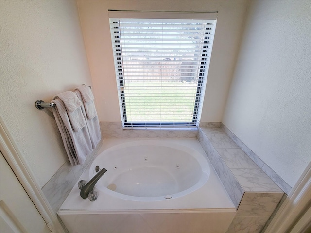 bathroom with a jetted tub and a textured wall