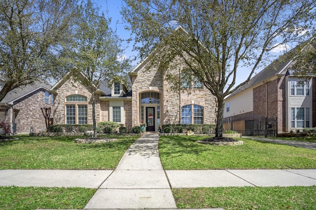 french country home with stone siding, brick siding, and a front lawn