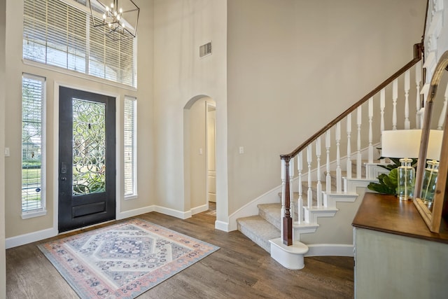 foyer with arched walkways, visible vents, a wealth of natural light, and wood finished floors