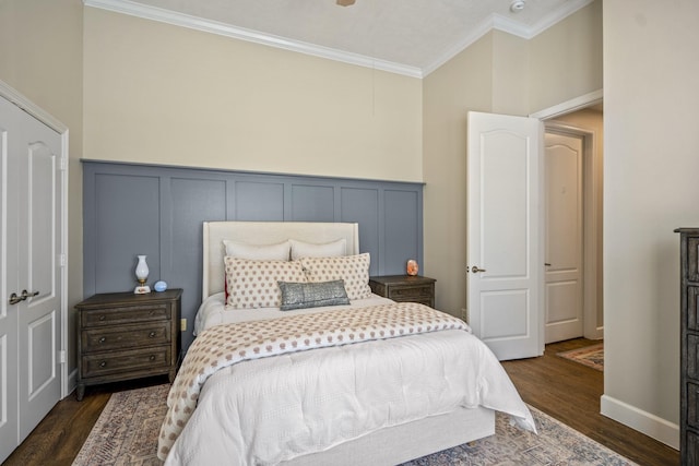 bedroom with a wainscoted wall, dark wood-type flooring, ornamental molding, and a decorative wall