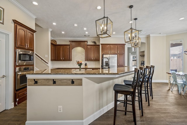 kitchen with dark stone countertops, a large island, appliances with stainless steel finishes, and dark wood-style floors