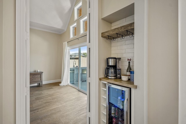 bar with wood finished floors, beverage cooler, lofted ceiling, a bar, and backsplash