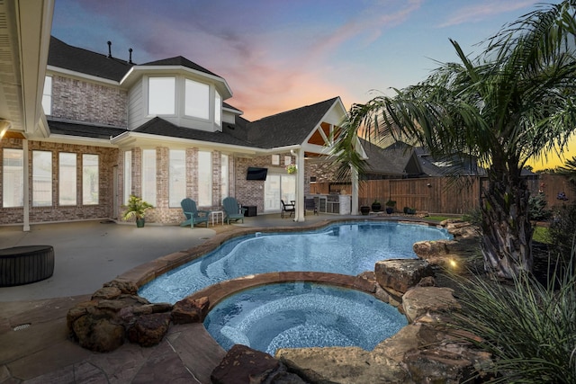 pool at dusk featuring a patio area, a fenced in pool, an in ground hot tub, and fence