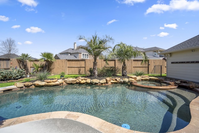 view of swimming pool featuring a pool with connected hot tub and a fenced backyard