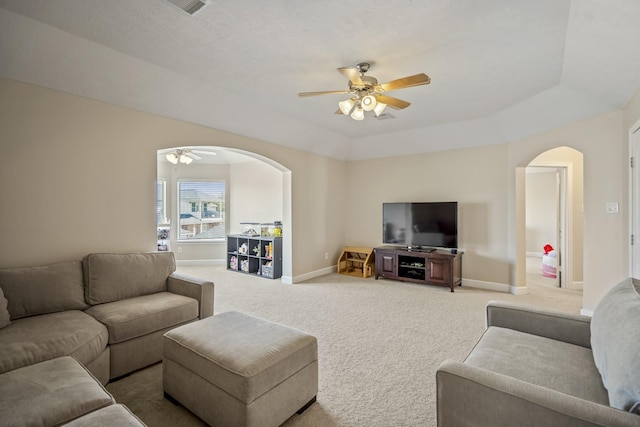 living area with light carpet, baseboards, arched walkways, and ceiling fan