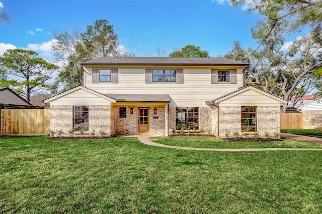 view of front of house with brick siding, a front yard, and fence