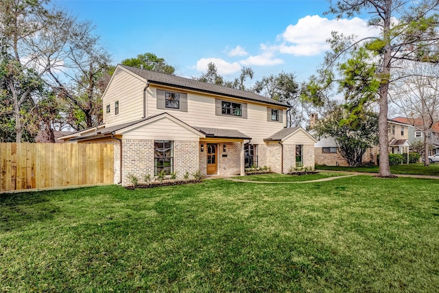 view of front of property with a front lawn, fence, and brick siding