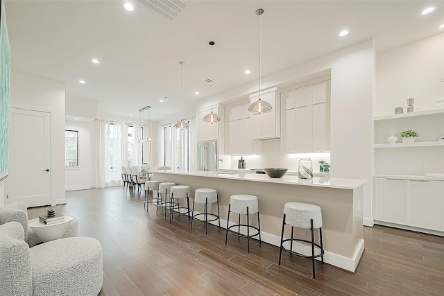 kitchen with a large island, white cabinetry, a breakfast bar area, and dark wood-style flooring