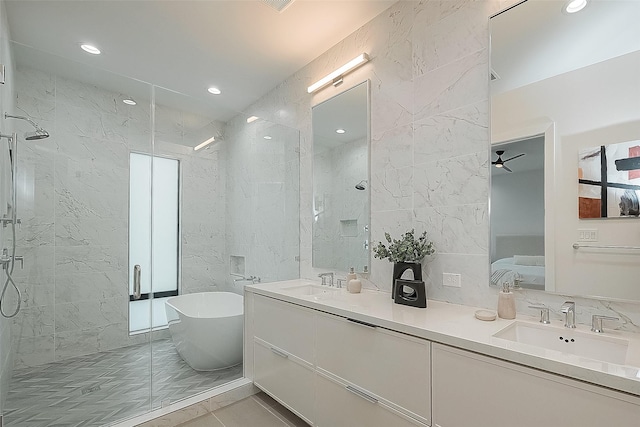 full bath with a shower stall, a freestanding tub, tile walls, and a sink