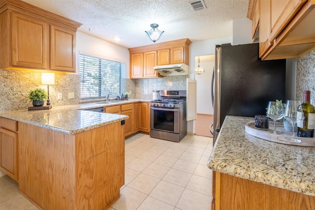 kitchen with visible vents, under cabinet range hood, a peninsula, stainless steel appliances, and a sink