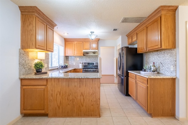 kitchen featuring visible vents, a peninsula, a sink, under cabinet range hood, and appliances with stainless steel finishes