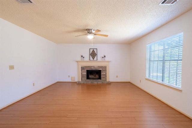 unfurnished living room featuring visible vents, a fireplace, a ceiling fan, and light wood-style floors