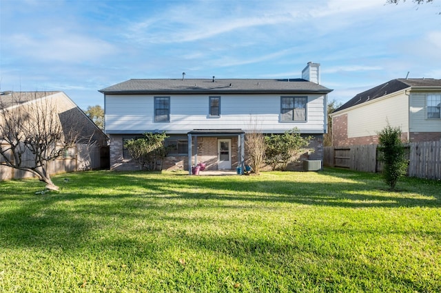 rear view of house featuring a yard, brick siding, a fenced backyard, and a chimney