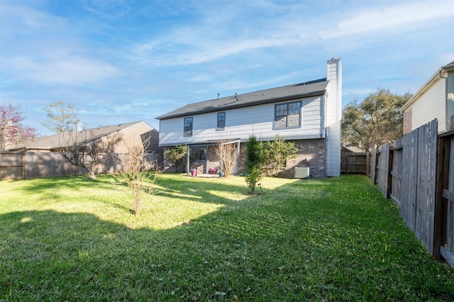 rear view of property with a lawn, central AC unit, a fenced backyard, and brick siding