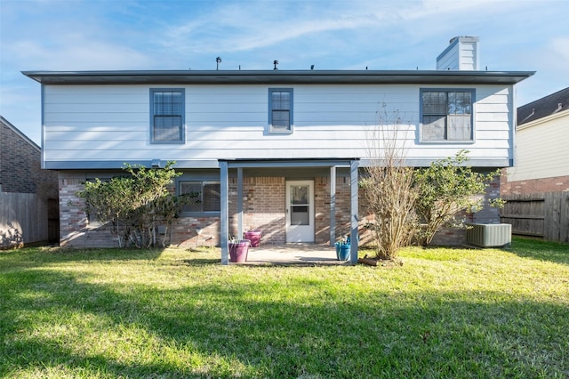 back of property with central air condition unit, fence, a yard, brick siding, and a patio area