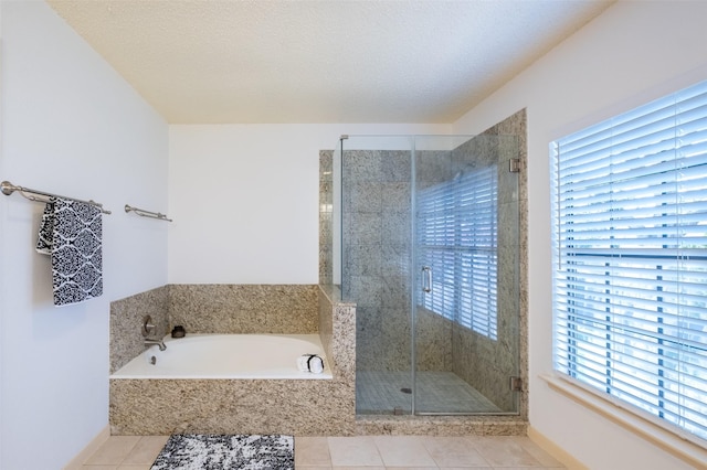 full bath with tile patterned flooring, a garden tub, a stall shower, and a textured ceiling