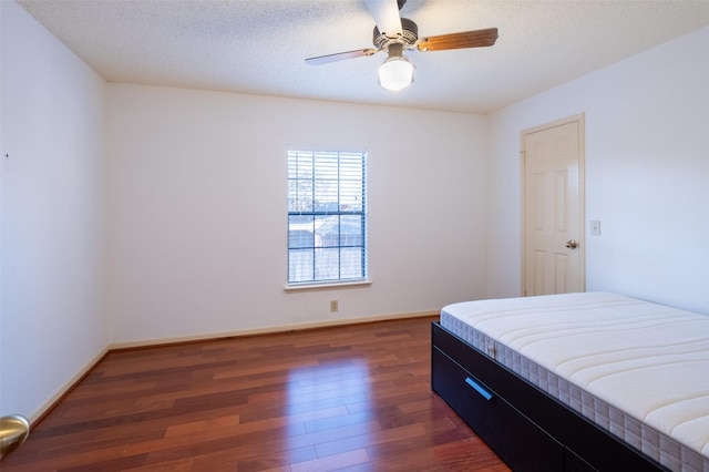 bedroom featuring wood finished floors, baseboards, and a textured ceiling