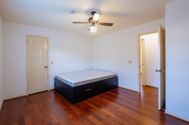 bedroom with a ceiling fan, dark wood-style floors, baseboards, and a textured ceiling