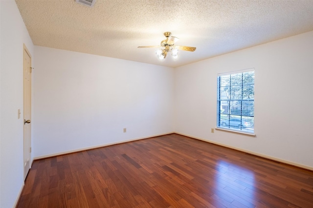 empty room featuring visible vents, a ceiling fan, a textured ceiling, wood finished floors, and baseboards