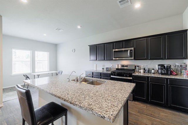 kitchen with a sink, stainless steel appliances, visible vents, and dark cabinetry