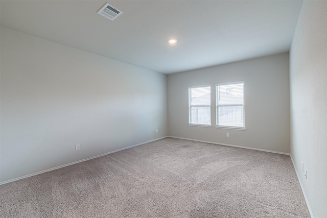 carpeted spare room with visible vents and baseboards