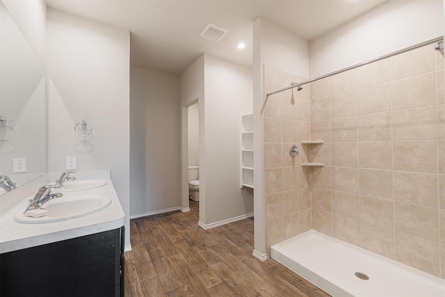 full bath with toilet, wood finished floors, visible vents, and a sink