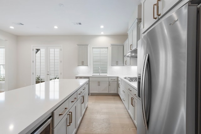 kitchen with visible vents, under cabinet range hood, light countertops, appliances with stainless steel finishes, and a sink