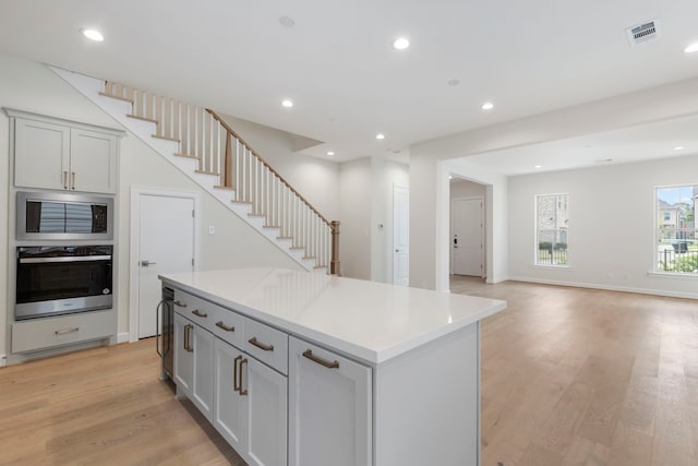 kitchen featuring light wood finished floors, recessed lighting, stainless steel appliances, light countertops, and a center island