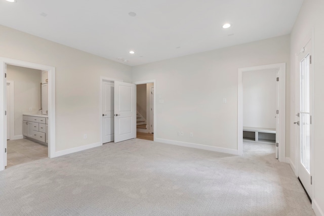 unfurnished bedroom with recessed lighting, light colored carpet, baseboards, and a sink