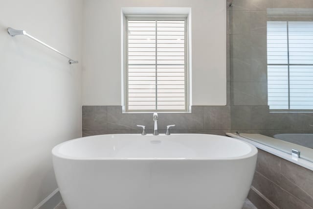 bathroom featuring tile walls and a freestanding tub