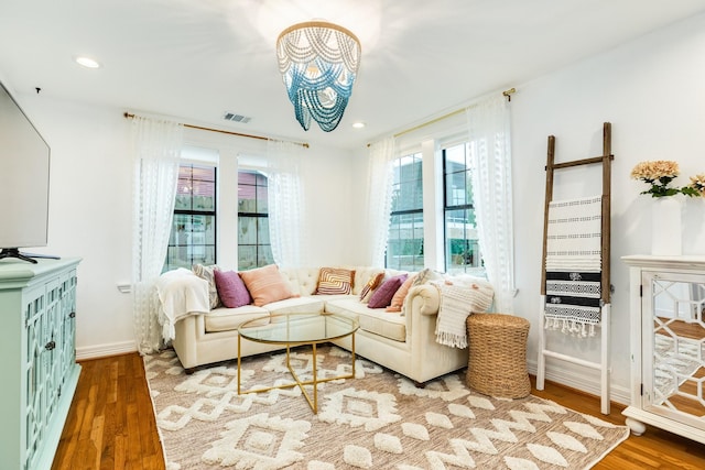 living room with recessed lighting, visible vents, baseboards, and wood finished floors