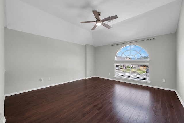 spare room featuring dark wood-style floors, a ceiling fan, lofted ceiling, and baseboards