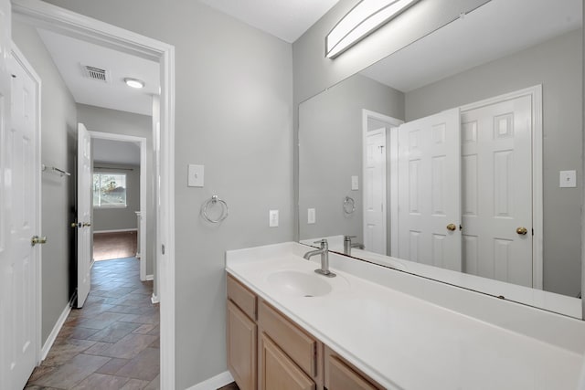 bathroom with visible vents, baseboards, stone tile flooring, and vanity